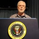 Ed Darrell tries out the Presidential podium and teleprompter