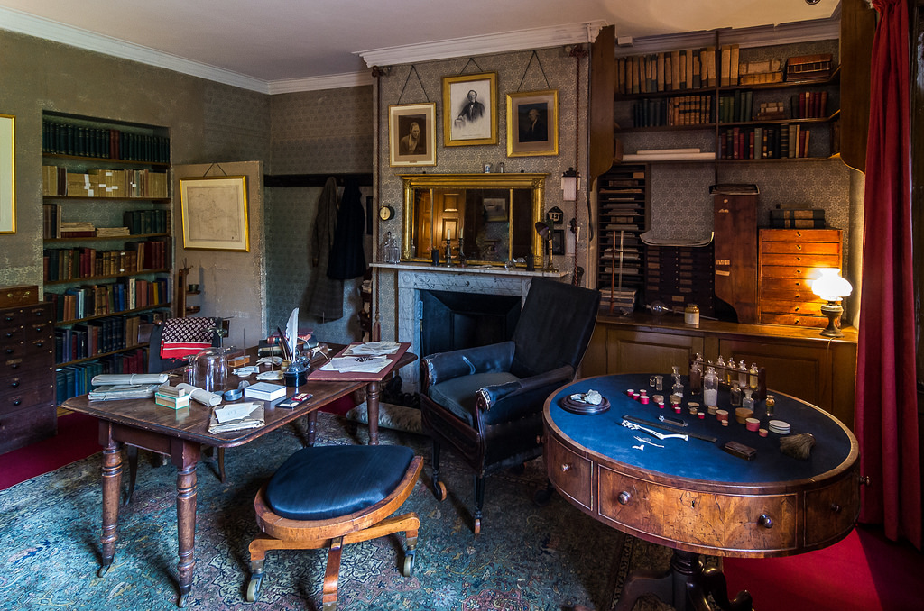 Charles Darwin's Study, Down House. Photo by and copyright held by Bob Radlinski. Radlinski's description: Darwin regularly spent about 5 hours a day here for 40 years and kept a chamber pot behind the partition so that he wouldn't have to trek to the toilet. But he still had time for an active family life with his wife Emma and their 10 children. The low stool with casters was used to spin himself from one desk where he dissected in front of the window to another where he took notes or wrote up labels—the stool the children were allowed to use for their games, punting themselves around the living room with long poles. The sitting room at the back of the house has large windows that go to the floor so that on nice days, the children (and dogs) could roam back and forth from house to garden at will.