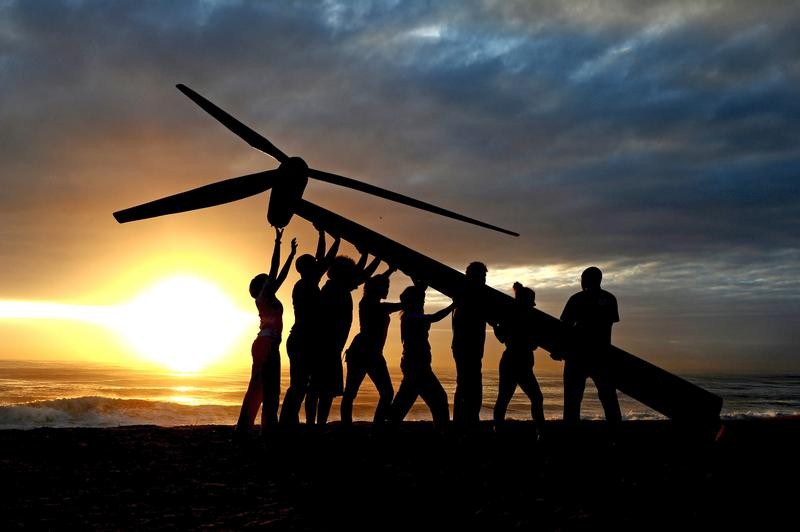 Greenpeace and Tcktcktck volunteers raise a wind turbine on the beach at dawn in Durban, South Africa. Microgrid News image